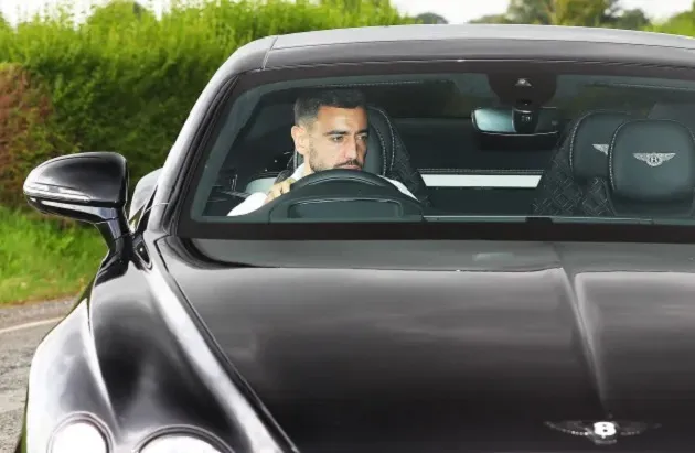Jadon Sancho hides from the cameras with his hood up in the car as he returns to Manchester United training - Bóng Đá