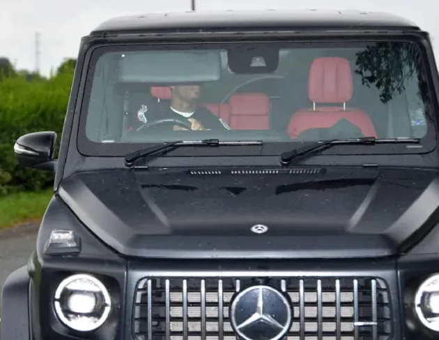 Jadon Sancho hides from the cameras with his hood up in the car as he returns to Manchester United training - Bóng Đá