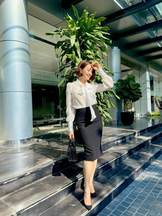 Công thức áo blouse trắng cổ nơ buộc và chân váy đen vừa nữ tính đồng thời tôn dáng cao ráo, thon gọn hơn. 