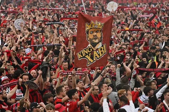 Xabi Alonso is covered in beer as his jubilant Bayer Leverkusen players gate-crash his post-match press conference - Bóng Đá