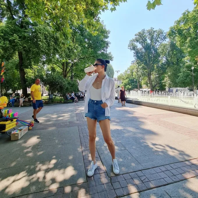 Ngô Thanh Vân diện áo tank top, sơ mi trắng, quần denim short và giày sneaker.