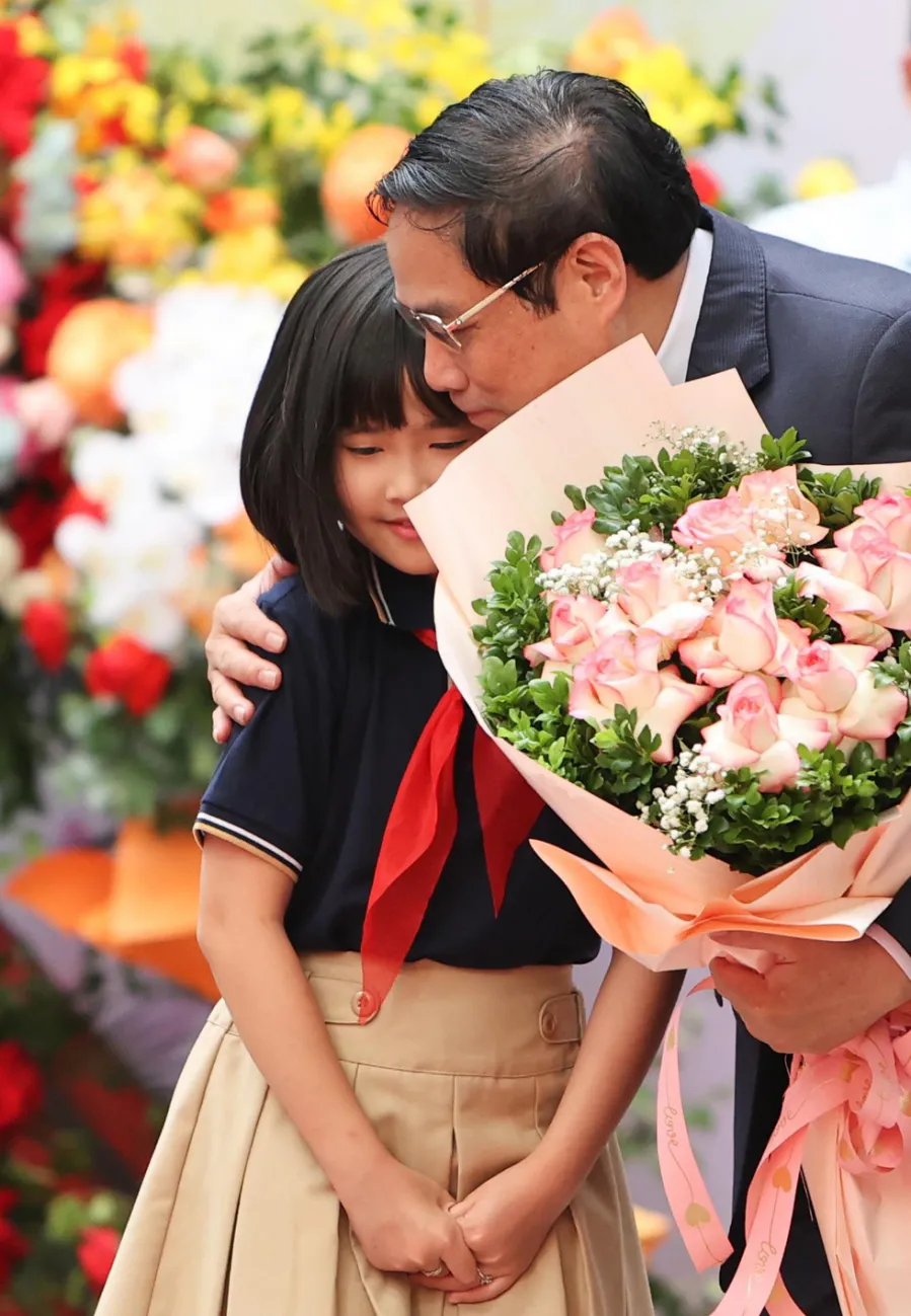 Thủ tướng Phạm Minh Chính nhận bó hoa từ một học sinh tại trường tiểu học Đoàn Thị Điểm (Hà Nội) - Ảnh: NGUYỄN KHÁNH